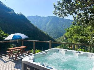 bañera de hidromasaje en una terraza con mesa y sombrilla en ハイランドビュー, 