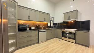 Luxurious Al Danah 5BR Family Friendly Getaway في أبوظبي: مطبخ مع أجهزة ستانلس ستيل ودواليب بيضاء