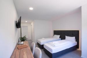 ein Schlafzimmer mit zwei Betten und einem Holztisch in der Unterkunft SMARTHOTEL Aalen in Aalen