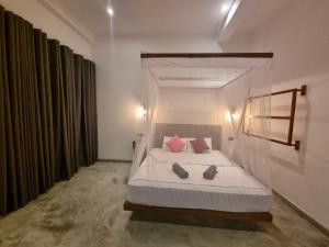 a bedroom with a white bed with red pillows at Danu Surf House Hiriketiya in Dickwella
