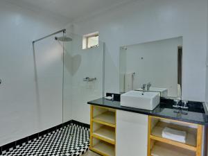 une salle de bain avec un lavabo et une douche en verre dans l'établissement ANEW Resort White River Mbombela, à White River