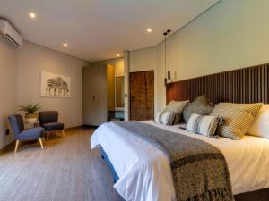 a bedroom with a large bed and a chair at Tenkudu Bush Lodge in Dinokeng Game Reserve