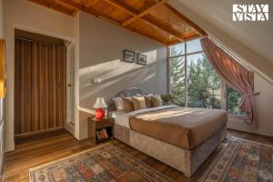 a bedroom with a bed and a large window at StayVista at Emaarat Chalet with BBQ & Bonfire in Srinagar