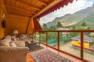 a living room with a view of a mountain at StayVista at Emaarat Chalet with BBQ & Bonfire in Srinagar