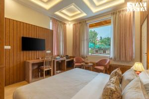 a hotel room with a bed and a desk and a television at StayVista at Emaarat Chalet with BBQ & Bonfire in Srinagar