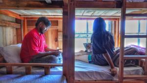 two people sitting on beds in a bunk bed at Stargaze Backpackers Ziro in Ziro