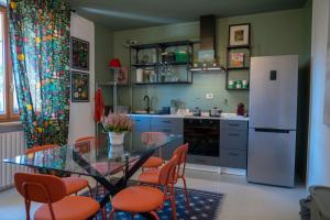 a kitchen with a glass table and chairs and a refrigerator at Clarín Rooms in Cuneo