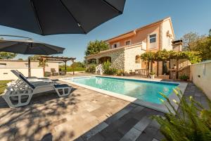 a swimming pool with chairs and an umbrella next to a house at Holiday House Laetitia with pool in Banjevci