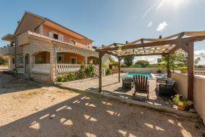 a backyard with a pergola and a swimming pool at Holiday House Laetitia with pool in Banjevci