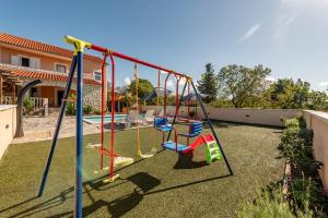 a playground with slides and swings in a backyard at Holiday House Laetitia with pool in Banjevci