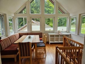 a dining room with a table and chairs and windows at Ferienwohnung Hüttenbauer in Dorf