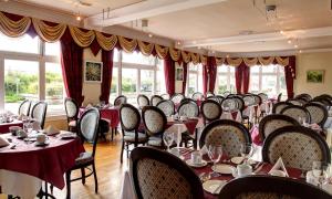 a dining room with tables and chairs and windows at The Imperial Hotel in Fort William
