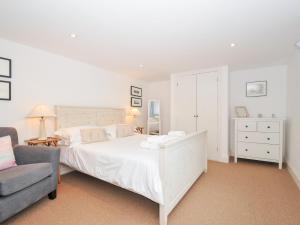 a bedroom with a white bed and a couch at Orchard Cottage in Saint Endellion