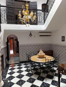 Riad kech residence al Qarya syahiya Marrakech في مراكش: غرفة طعام مع طاولة وثريا