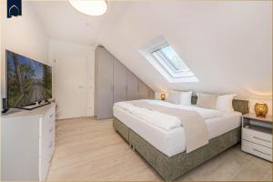 una camera da letto bianca con un letto e una televisione di FeWo Kleckerburg a Kolpinsee