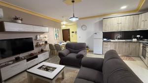 a living room with a couch and chairs and a kitchen at Your Home in Pogradec