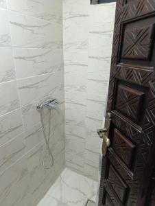 Riad kech residence al Qarya syahiya Marrakech في مراكش: حمام مع دش مع باب خشبي