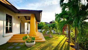 een huis met een veranda met palmbomen in de tuin bij Luxury Pool Villa - Sawan - 4 Bedroom in Hua Hin