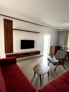 a living room with a red couch and a flat screen tv at Stylish 1-Bedroom Apartment in Kigali +10 photos