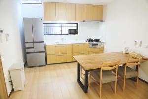 Una cocina con una mesa de madera y un refrigerador. en 雅舍8大阪南海線岸里玉出駅1min新開業一户建貸切100平米可駐車, en Osaka