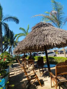 a group of chairs and a straw umbrella on a beach at Hakuna Matata Ocean View Home - Msasani Near Masaki in Dar es Salaam +20 photos
