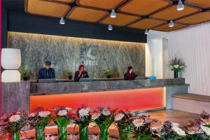 drei Personen sitzen an einem Tresen in einer Lobby mit Blumen in der Unterkunft The K Hotel, WorldHotels Distinctive in Manama