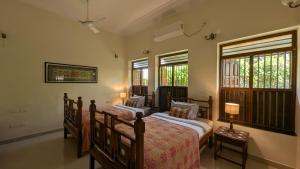 two beds in a bedroom with two windows at Saranyam by LuxUnlock Private Villas in Kāraikkudi