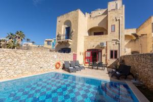 a house with a swimming pool in front of a building at Make a Splash! 3BR Farmhouse, Pool & Country Views in Munxar