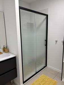 a glass shower in a bathroom with a sink at Appartement neuf in Linxe