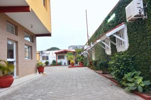 una pasarela adoquinada entre dos edificios con plantas en Hotel Ophelia Lodge, en Port-Gentil 7 fotos más
