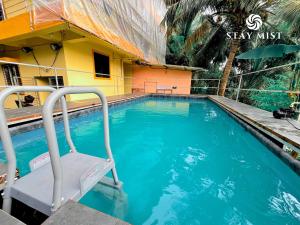 a swimming pool in front of a house at StayMist - Ocean Lemon Pool Villa with Jacuzzi in Alibaug