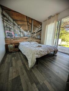 a bedroom with a bed and a wooden floor at L'échappée médocaine, deux maisons indépendantes in Cussac-Fort-Medoc