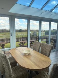 a wooden table and chairs in a room with windows at The Milking Parlour in Aberystwyth
