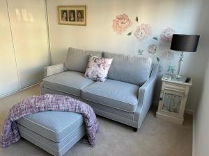 een woonkamer met een bank en een poef bij Elite Stay Ladies Only in Port Macquarie