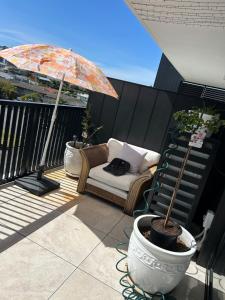 een patio met een stoel en een parasol op een balkon bij Elite Stay Ladies Only in Port Macquarie