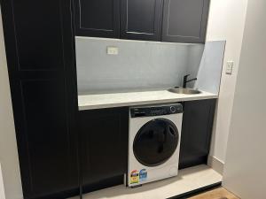 een wasmachine in een keuken met zwarte kasten bij Elite Stay Ladies Only in Port Macquarie
