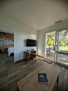 a living room with a flat screen tv and a table at L'échappée médocaine, deux maisons indépendantes in Cussac-Fort-Medoc
