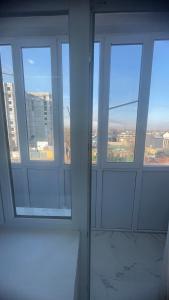 a room with three windows with a view of a city at Проспект Жамбыла 115а люкс квартира in Taraz