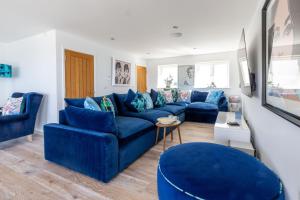 Una sala de estar con un sofá azul y sillas azules. en Tides Edge, en Portreath
