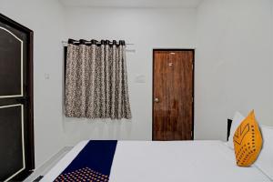 Un dormitorio con una cama y una puerta de madera. en Spot On Tulsi Stay Inn, en Nagpur 17 fotos más