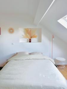 a white bedroom with a bed with a plant on the wall at Dreamz in Calais