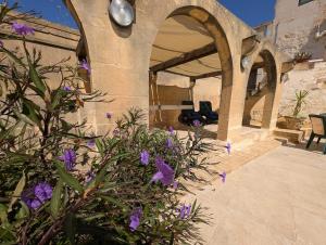 a house with purple flowers in front of a building at Gozitan Charm in Xaghra with Pool in Xagħra