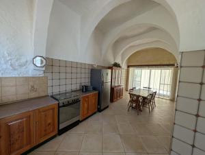 a kitchen with a stove and a table with chairs at Gozitan Charm in Xaghra with Pool in Xagħra
