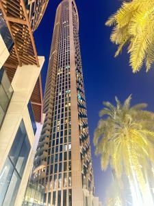 a tall building with palm trees in front of it at Private Sea View Room in 3BR Downtown Apartment Direct Mall & Metro Access in Dubai