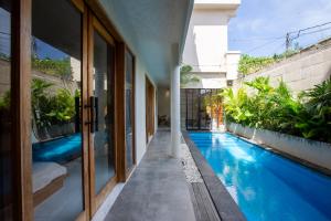 a house with a swimming pool next to a building at Casa Ombak in Kerobokan