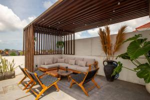 a patio with a couch and two chairs and a table at Casa Ombak in Kerobokan