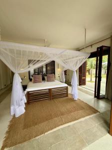 une chambre avec un grand lit à baldaquin dans l'établissement Maya kobe Beachfront Retreat Kilifi, à Kilifi