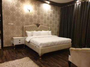 une chambre avec un lit blanc et un canapé dans l'établissement Royal Villa Islamabad, à Islamabad