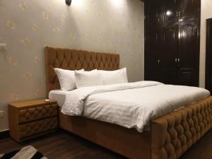 une chambre avec un grand lit avec des draps blancs dans l'établissement Royal Villa Islamabad, à Islamabad 17 autres photos