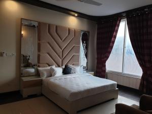une chambre avec un grand lit et une grande fenêtre dans l'établissement Royal Villa Islamabad, à Islamabad
